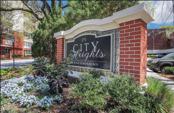 Entrance signage of City Heights Condominiums with surrounding greenery.