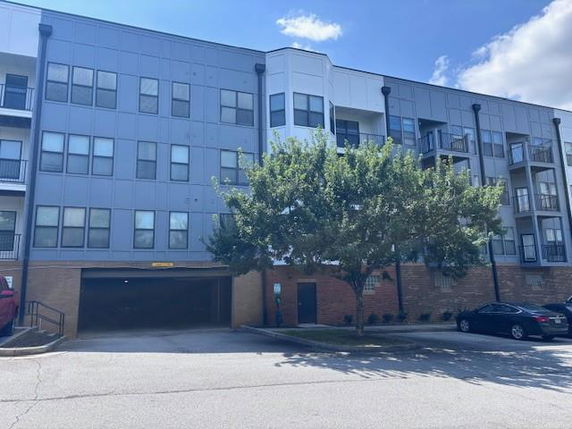Front view of a multi-story residential building with balconies and a parking area.
