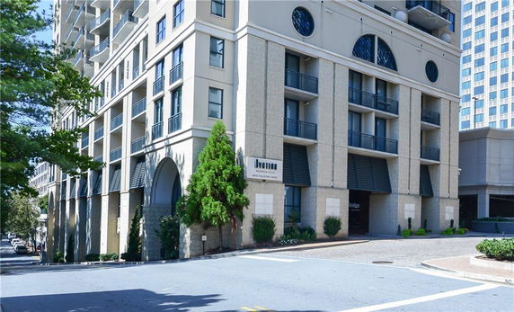 Front view of a multi-story building with balconies and arched windows.