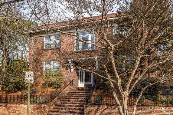 Front view of a two-story brick house with stairway leading to entrance.