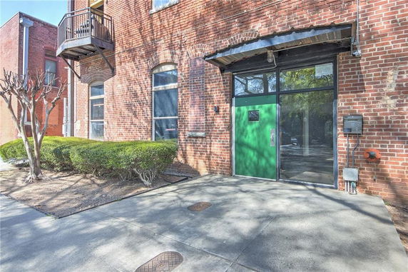 Front view of a brick building with a green door and a small balcony.