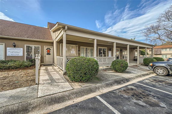 Front view of a single-story building with a porch and parking area.