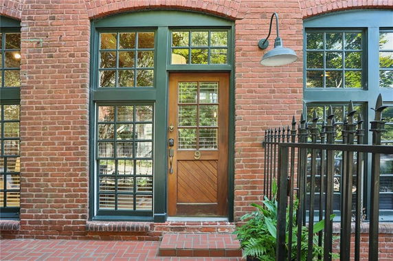 Front view of a red brick building with large windows and a wooden door.