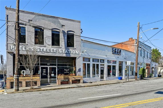 Front view of a two-story commercial building called Peters Street Station and adjacent storefronts.