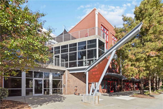 Front view of a modern multi-story building with large glass windows and brick facade.