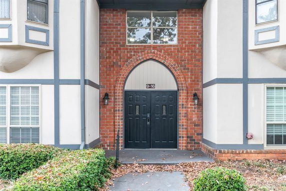 Front view of a building entrance with arched brick design and double doors.