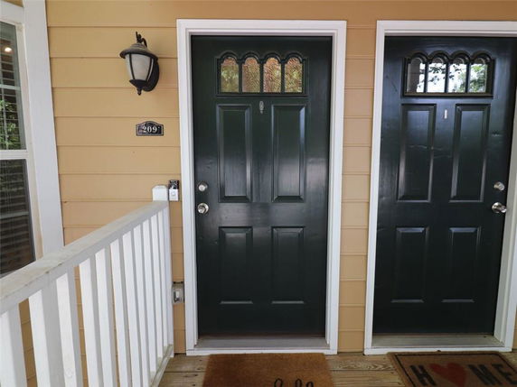Front view of a house entrance with black doors and a light fixture.