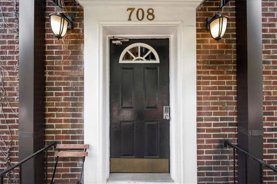 Front view of a residential building with a dark door and brick facade.