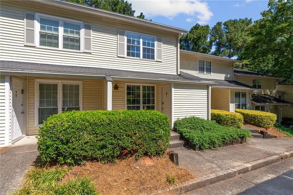 Front view of a multi-story townhouse with beige siding and white-trimmed windows.