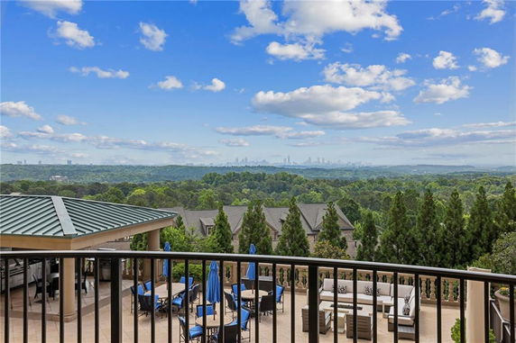 Panoramic view from a patio with seating and a distant city skyline.