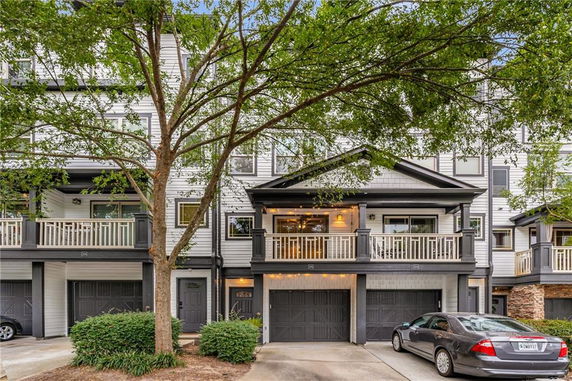 Front view of a multi-story townhouse with balconies and garages.