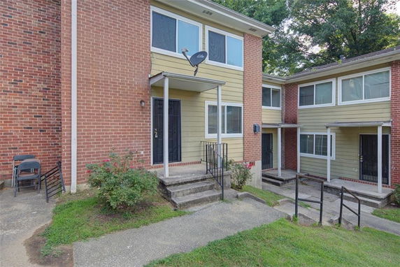 Front view of a two-story townhouse with a small porch and brick siding.