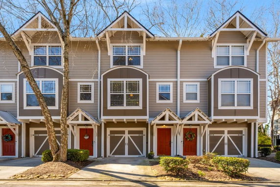 Front view of a multi-story townhouse with a distinct architectural design and red doors.