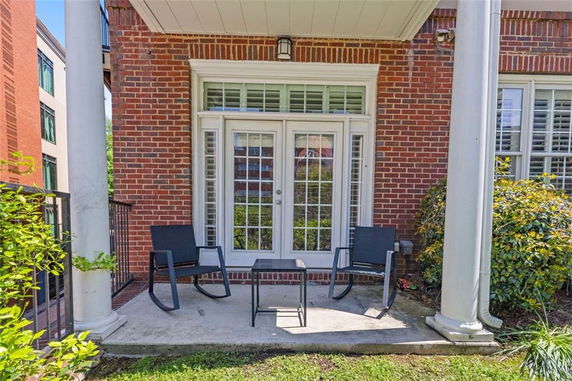 Front view of a brick facade with a patio and double glass doors.