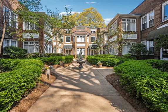 Front view of a two-story brick building entrance with large windows and landscaped walkways.