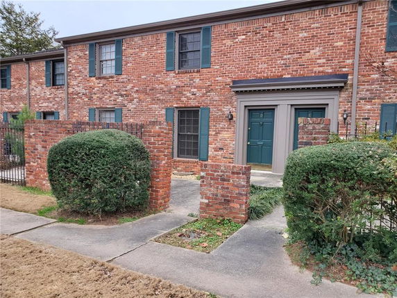 Front view of a two-story brick townhouse with green shutters.
