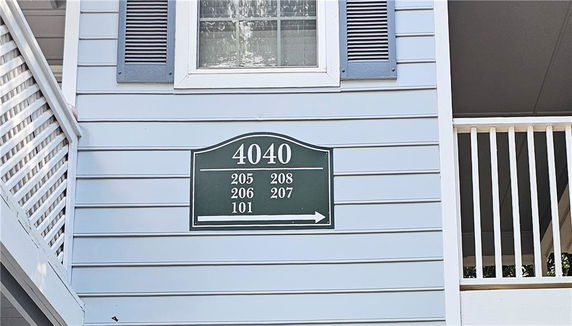 Front view of a building with horizontal siding, window, shutters, and directional sign for building 4040.