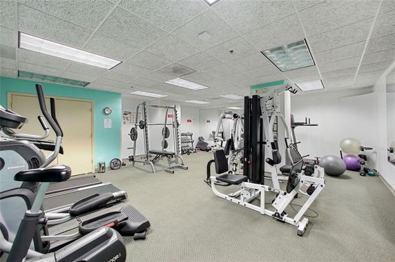 Room with exercise equipment including treadmills, weight machines, and exercise balls.