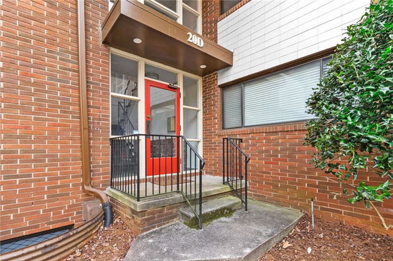 Front entrance of a building with a red door and brick exterior.
