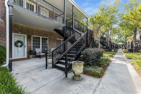 Front view of a multi-story brick residential building with balconies and outdoor stairs.