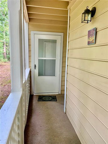 Entrance door of a house with exterior siding and a porch light.