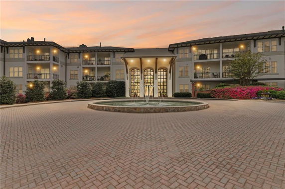 Front view of a multi-story building with balconies and central fountain.