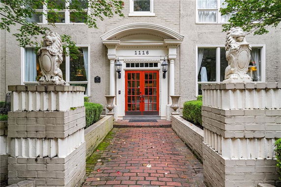 Front entrance of a building with red door and brick pathway.