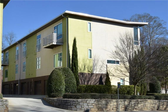 Front view of a modern multi-story building with balconies and a driveway.