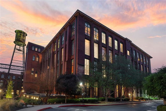 Front view of a large multi-story brick building with tall windows and an adjacent water tower.