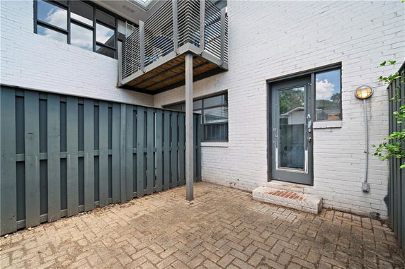 Outdoor view of a house section with a brick facade and a small balcony.