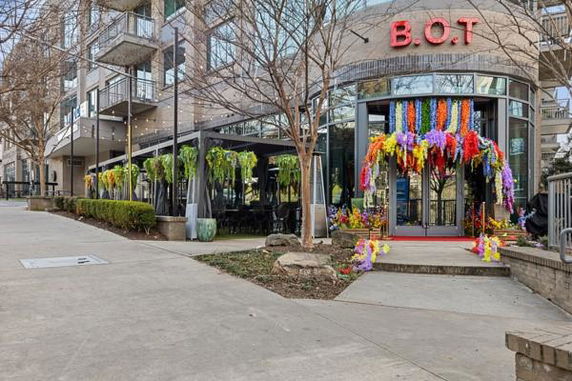 Front view of a modern commercial building with decorative plants and flowers at the entrance.