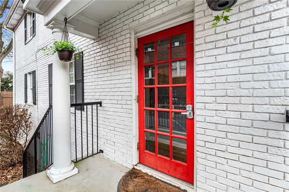 Close-up view of a house entrance with a bright red door and white brick exterior.