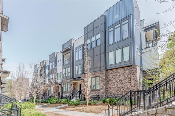 Front view of a multi-story modern apartment complex with large windows and brick accents.