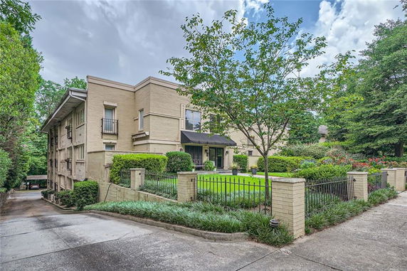 Front view of a multi-story building with a driveway and landscaped garden.