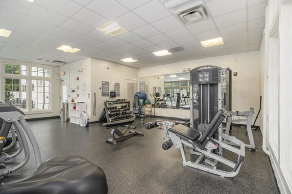Indoor gym area with exercise equipment including weights and machines.