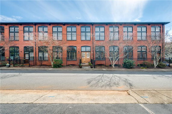 Front view of a two-story brick building with multiple large windows.