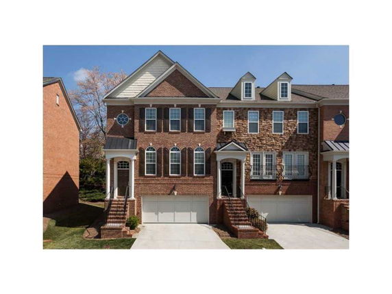 Front view of multiple attached houses with garages and brick facades.