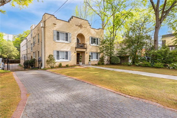 Front view of a two-story house with arched entrance and decorative windows with shutters.