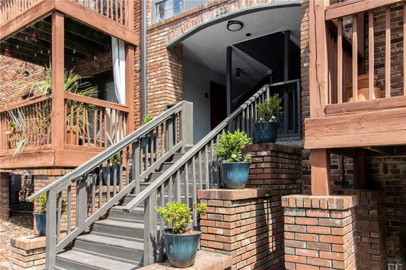 Front view of a brick building with outdoor staircases and wooden railings.