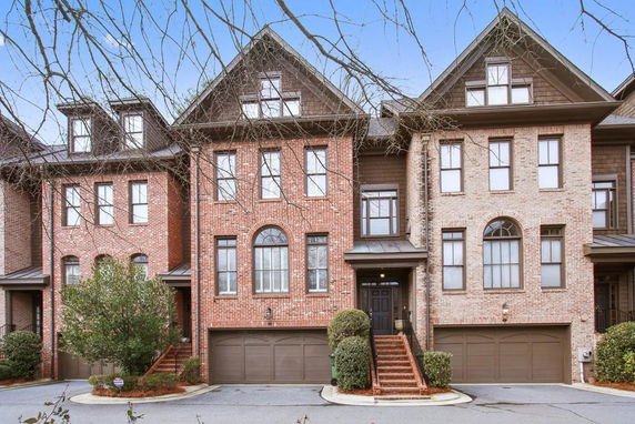 Front view of a multi-story brick townhouse with double garage.