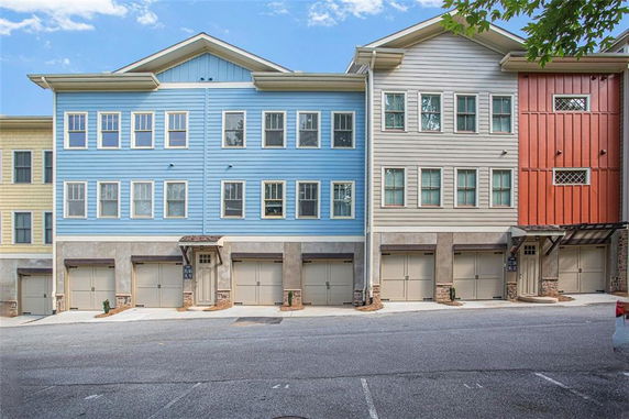 Front view of a row of multi-story houses with garages at the ground level.