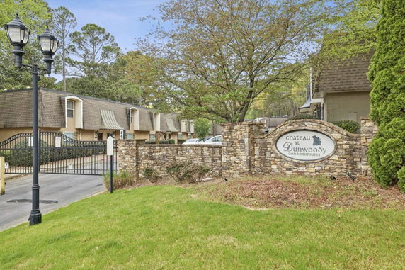 Front view of a gated condominium complex with multi-story buildings and a stone entrance sign.