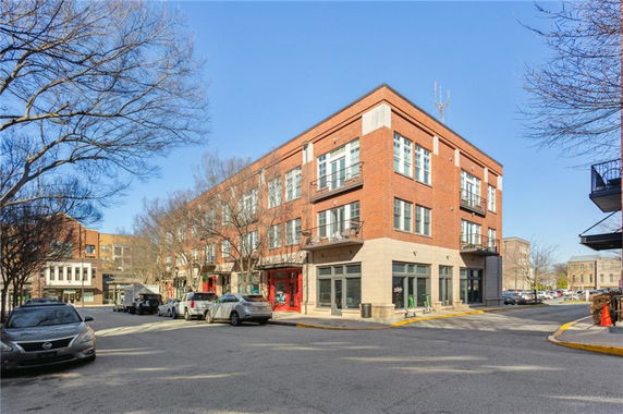 Front view of a three-story brick building with large windows and a street corner location.