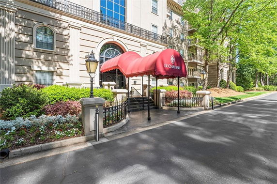 Front view of a multi-story building with an arched entrance and red canopy.