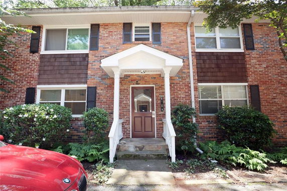 Front view of a brick facade two-story house with a covered entryway.