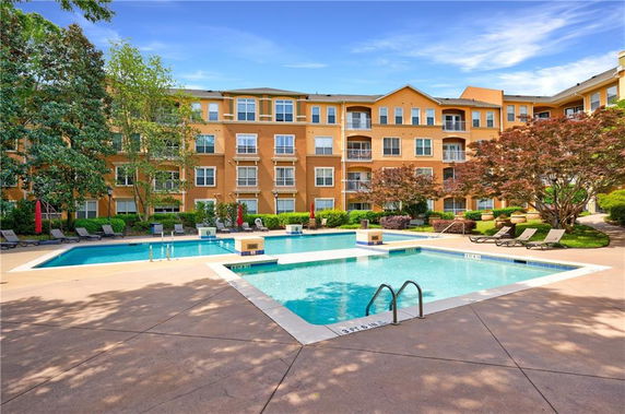 Outdoor view of a complex with a swimming pool and a multi-story building in the background.