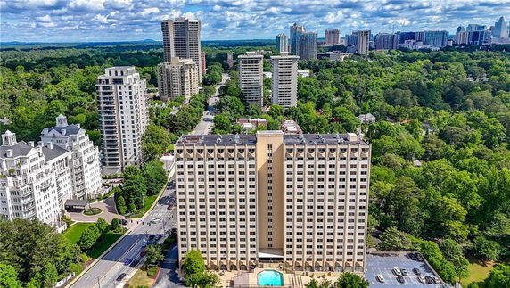 Front view of a high-rise building surrounded by trees and other tall buildings.