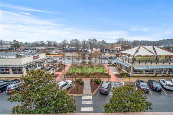 Panoramic view of a commercial area with parking, shops, and a plaza.