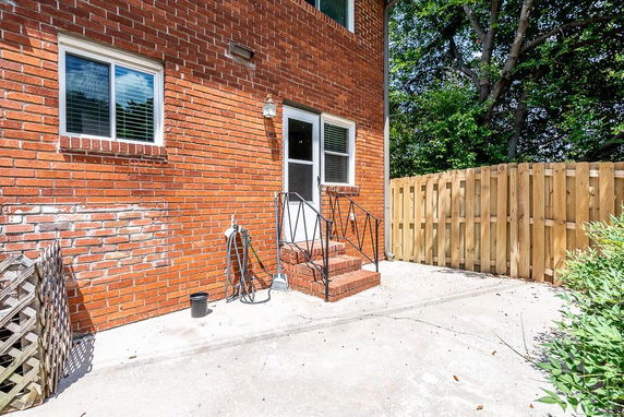 Side view of a red brick house with steps leading to a door.