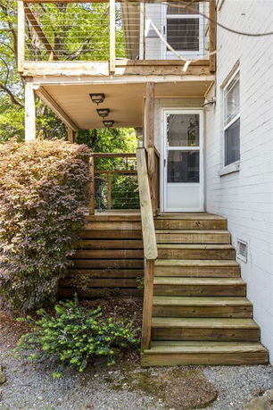 Backyard elevation with wooden stairs and a balcony.